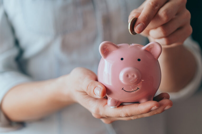 Person putting coins in piggy bank